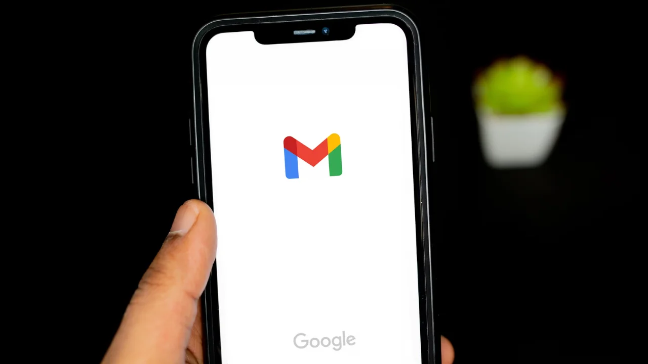 Gmail アプリを開いた状態で携帯電話を持っている手