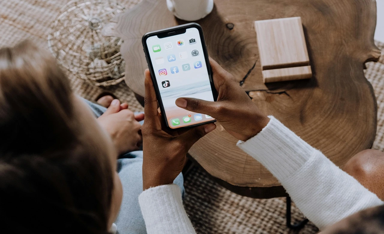 Two people looking at a smartphone screen with various social media icons