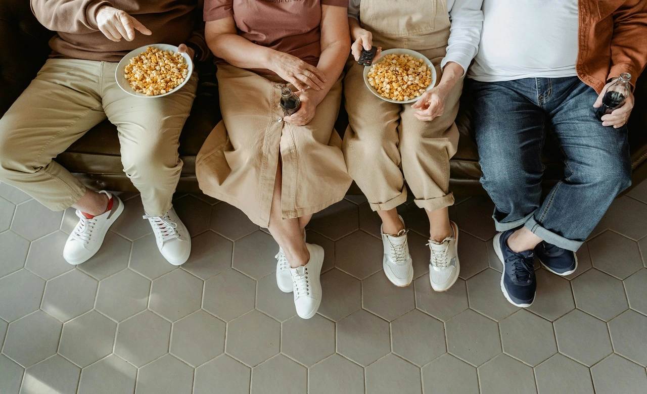 Four friends sitting on a couch eating popcorn